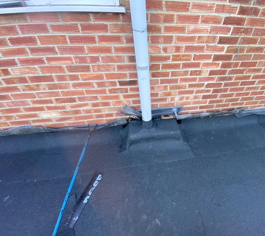 A new felt flat roof sealed around a downpipe
