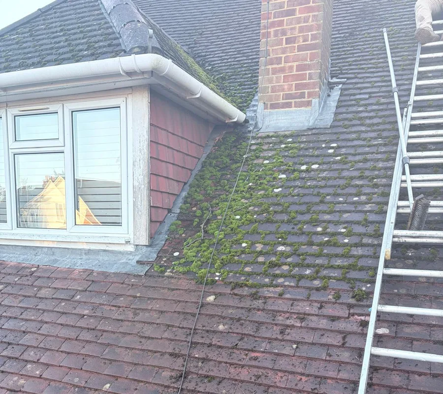 A tiled roof under repair beside a chimney